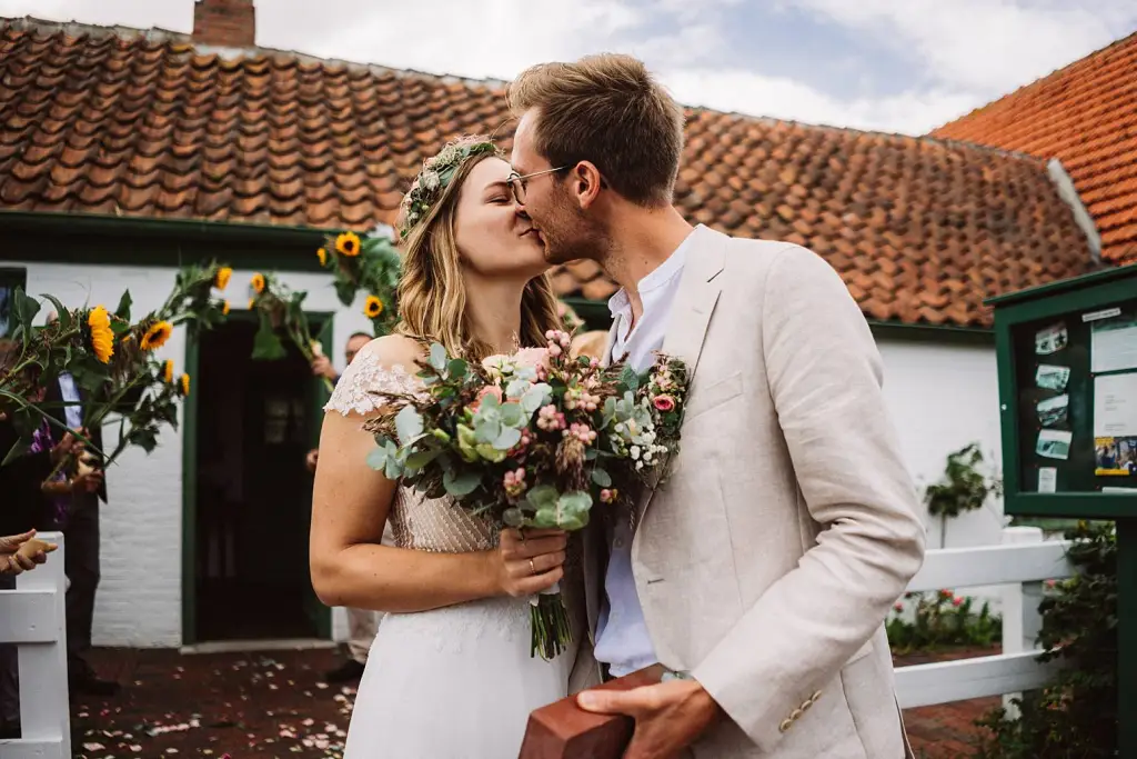Hochzeitsfotograf Langeoog – Brautpaar küsst sich vor dem Seemannshus