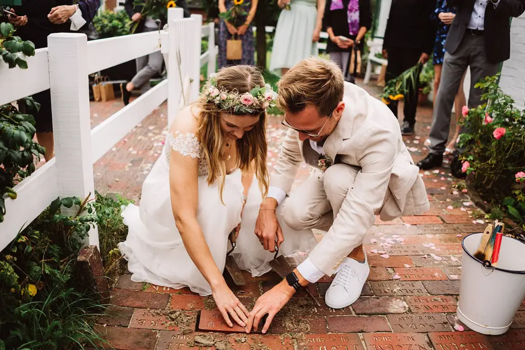 Hochzeitsfotograf Langeoog – Brautpaar beim Verlegen des Hochzeitsklinkers