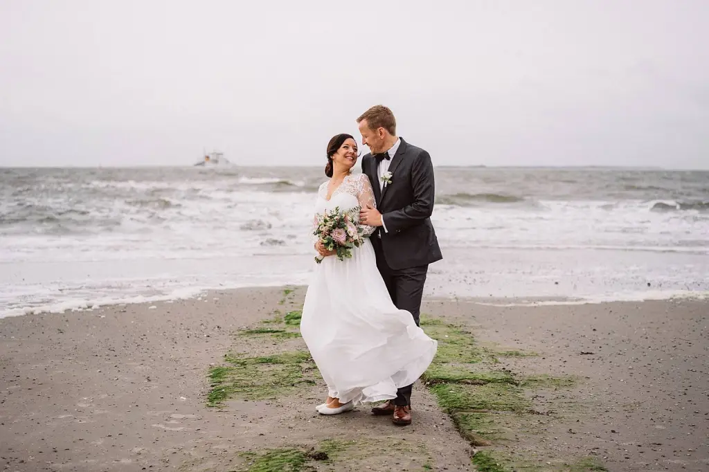 Hochzeitsfotograf Norderney – Brautpaar läuft lachend am Strand entlang