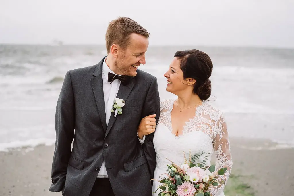 Hochzeitsfotograf Norderney – Brautpaar lacht beim Spaziergang am Strand