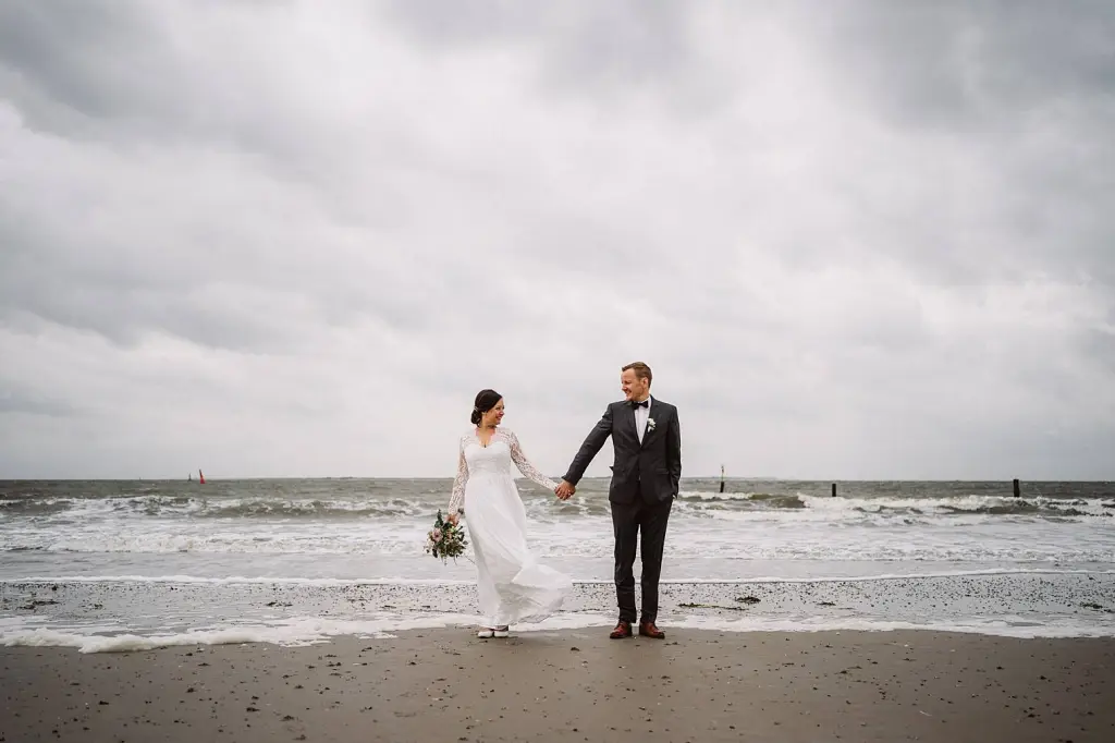 Hochzeitsfotograf Norderney – Brautpaar Hand in Hand am Meer