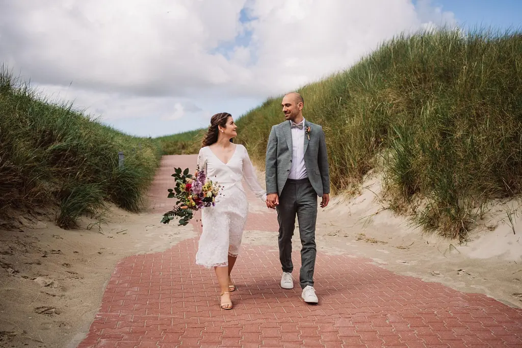 Hochzeitspaar auf dem Weg durch die Dünen