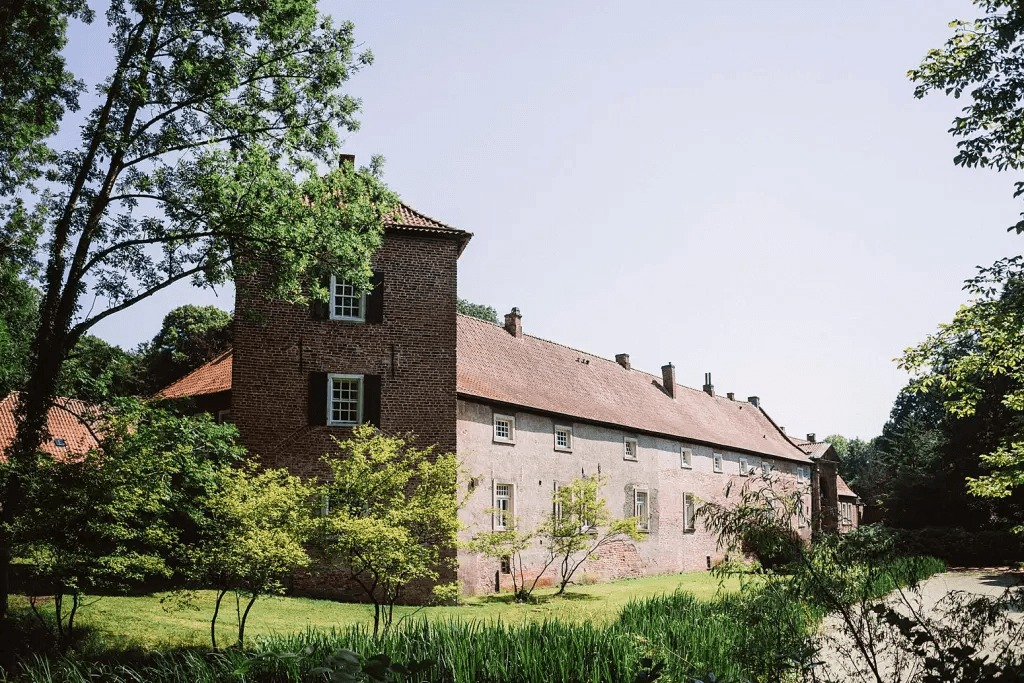 Hochzeitsfotograf Burg Berum – Außenaufnahme der Burg mit Graben und Bäumen