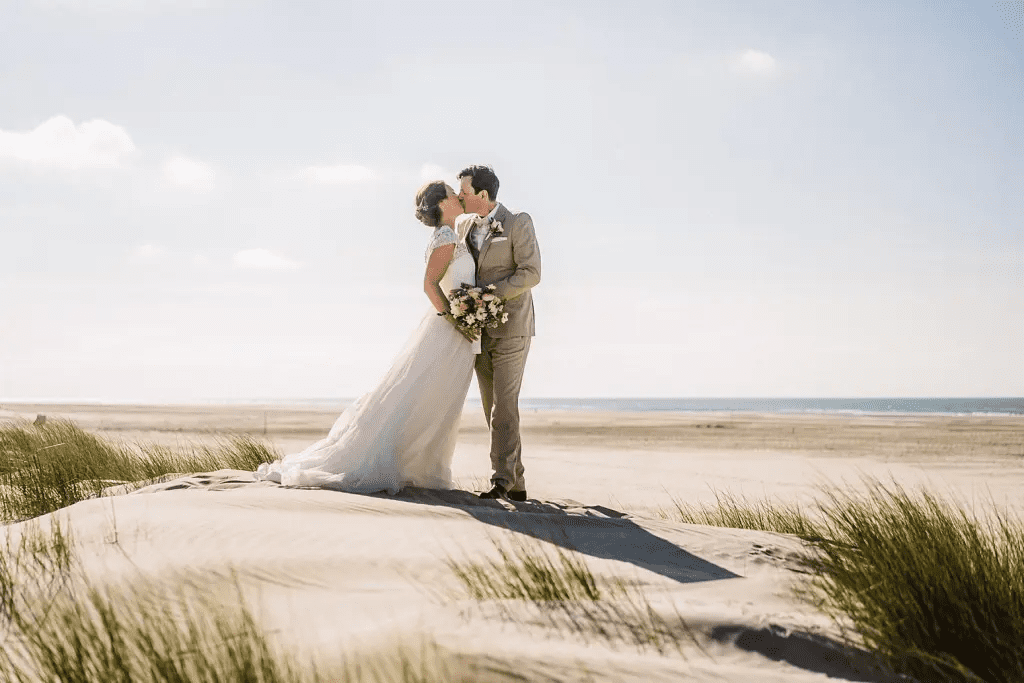 Brautpaar steht auf einer Düne am Strand von Juist – Hochzeitsfoto mit Blick auf Meer und Dünenlandschaft