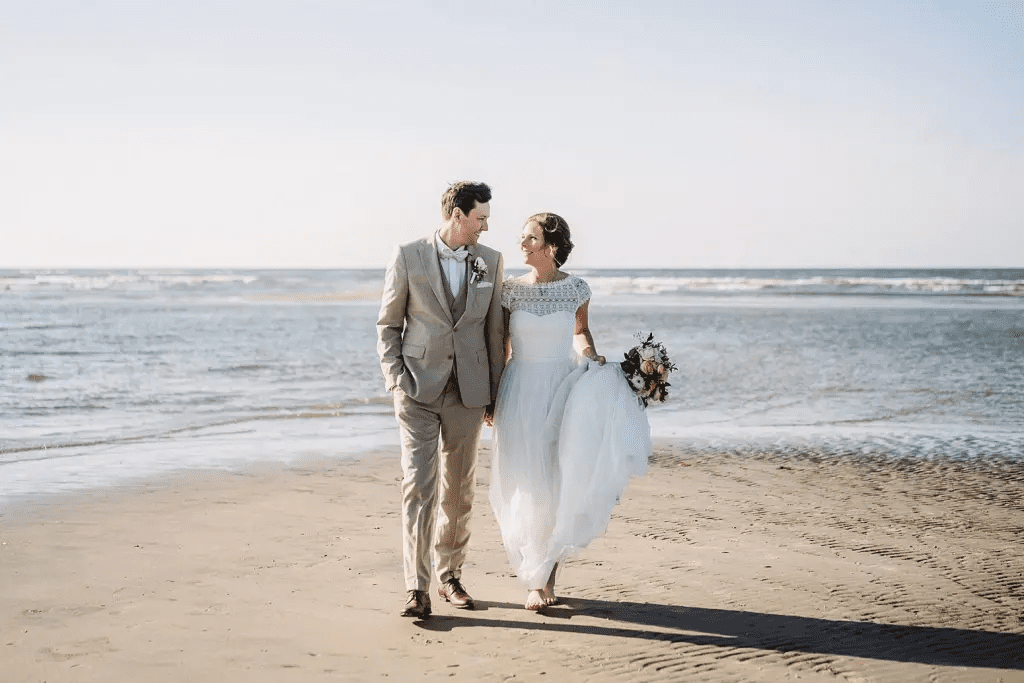 Brautpaar spaziert am Strand von Juist entlang – Hochzeitsfoto mit Meer und weichem Nordseelicht