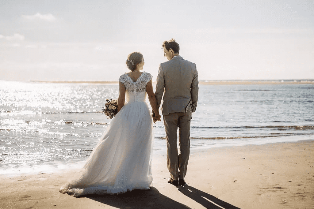 Brautpaar geht Hand in Hand am Strand von Juist – romantisches Hochzeitsfoto im Abendlicht an der Nordsee