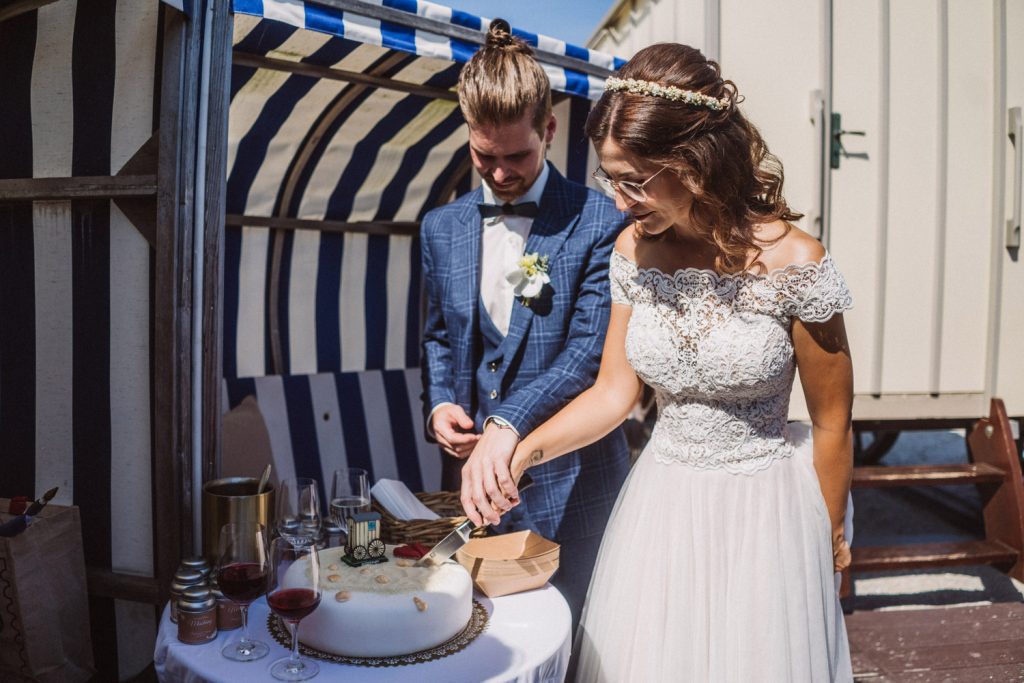 Brautpaar schneidet Hochzeitstorte am Strand von Norderney beim Badekarren an