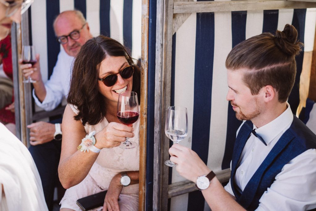 Bräutigam stößt nach der Trauung am Strand von Norderney mit Hochzeitsgästen an