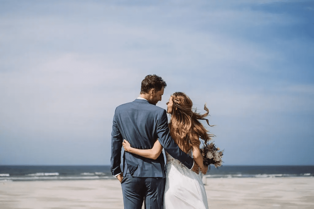 Hochzeitspaar am Strand von Juist blickt zum Meer