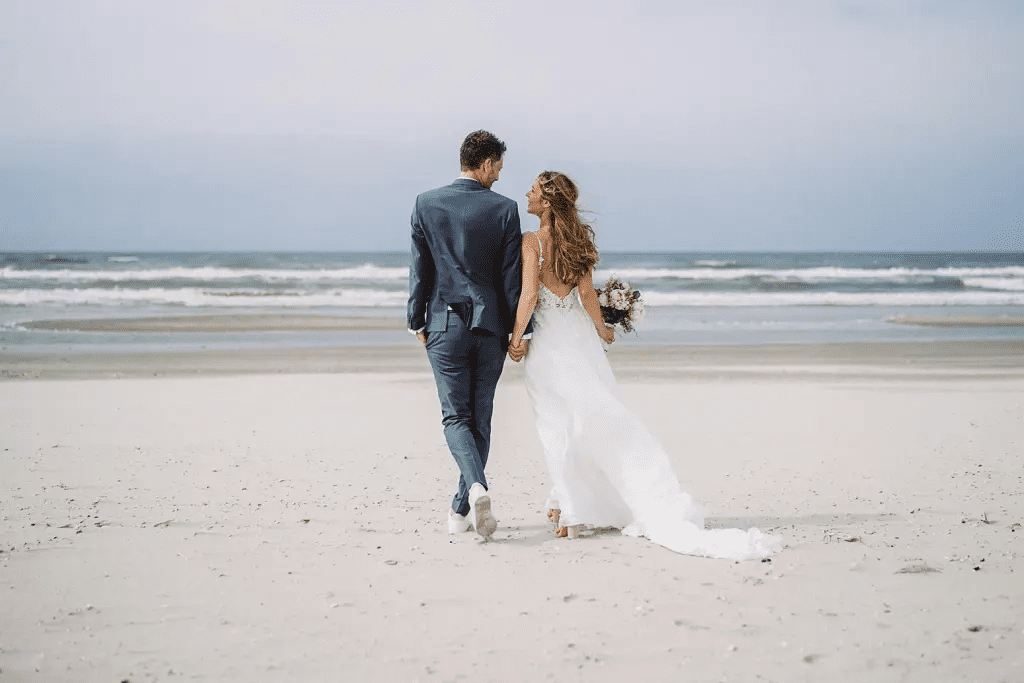 Brautpaar läuft Hand in Hand über den Strand von Juist – Weite, Wind und Nordseefeeling pur.