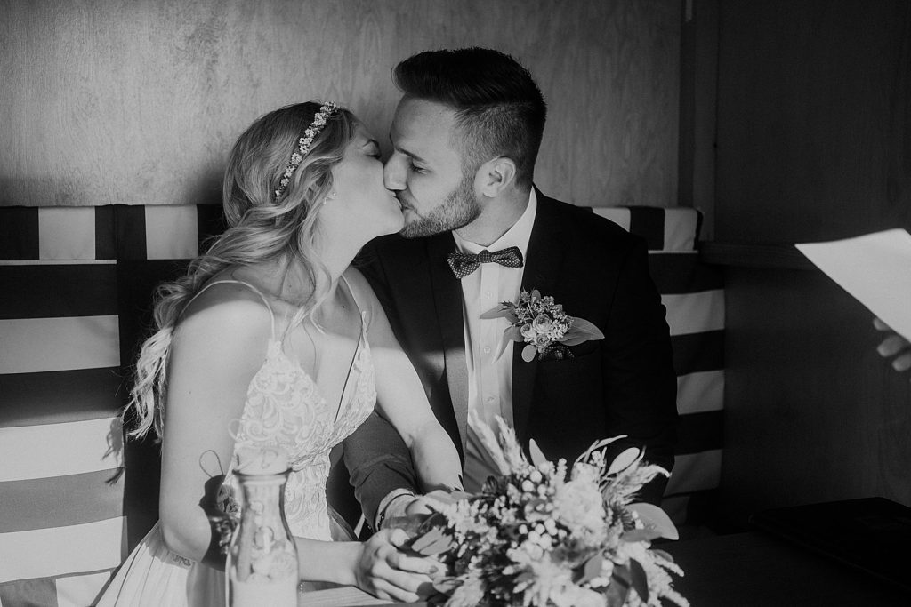 Brautpaar küsst sich nach der Trauung im Badekarren – intimer Moment im Strandkorb-Ambiente.