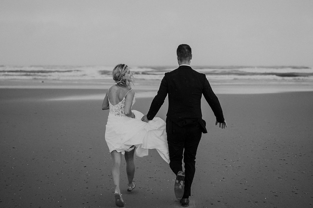 Braut und Bräutigam laufen Hand in Hand über den leeren Strand von Norderney – echtes Inselfeeling.