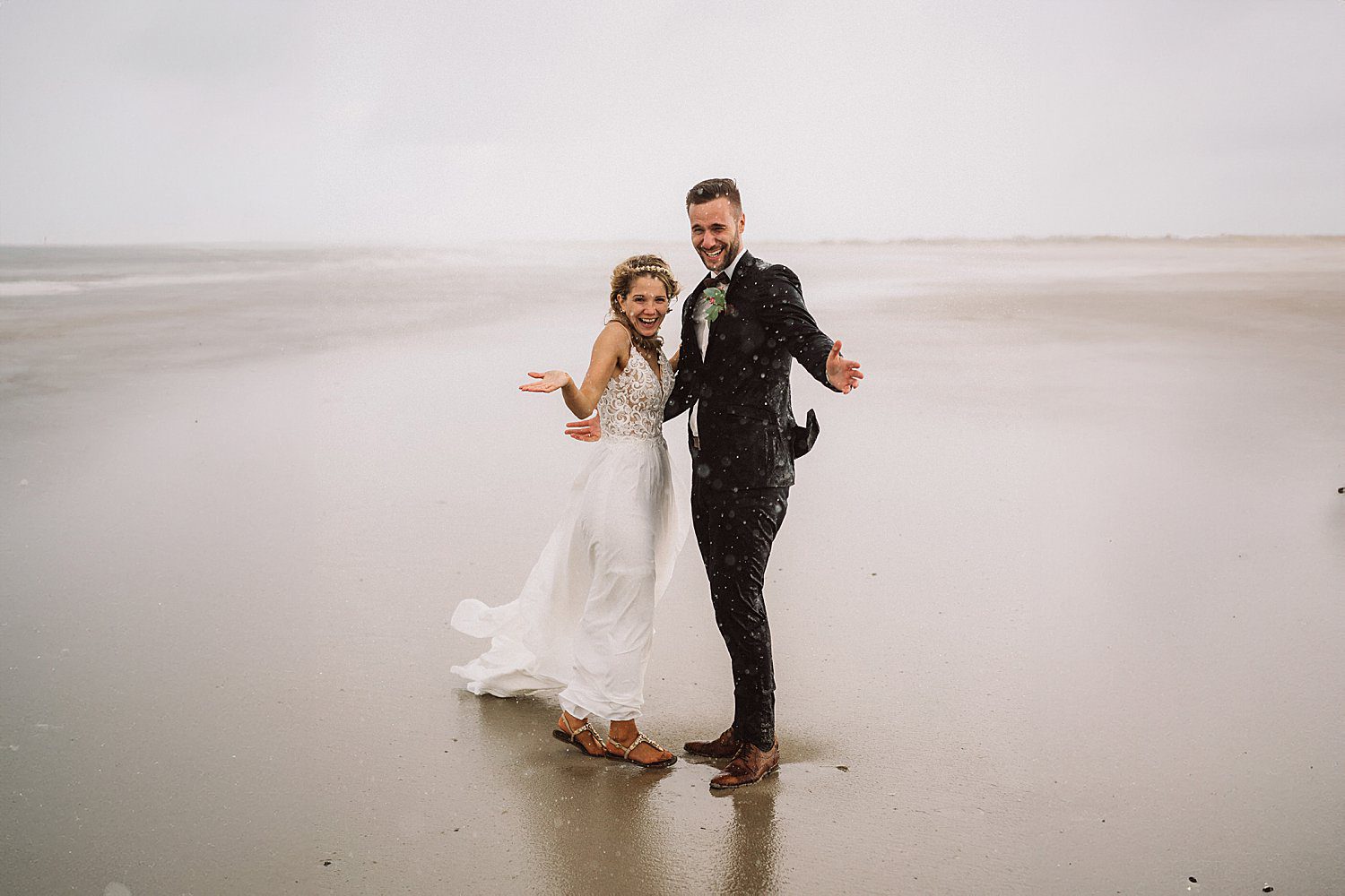 Brautpaar lacht im strömenden Regen am Strand von Norderney – emotionale, natürliche Hochzeitsfotos.