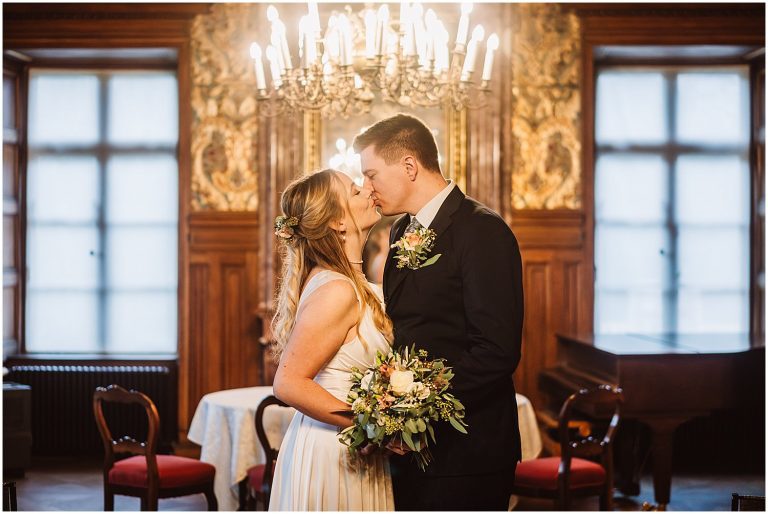 Romantischer Kuss des Brautpaares im Trausaal von Schloss Jever, winterliche Atmosphäre.
