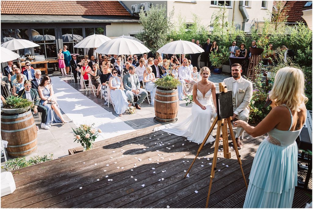 Brautpaar während der freien Trauung im Müggenkrug Oldenburg – Gäste hören aufmerksam zu