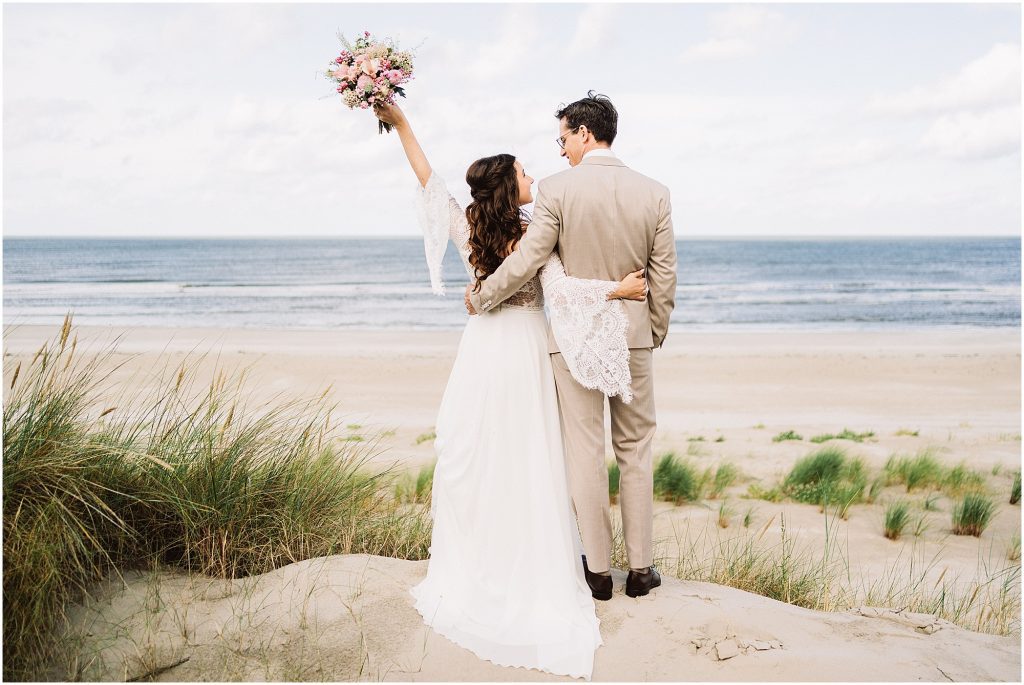 Brautpaar blickt gemeinsam aufs Meer bei einer Inselhochzeit auf Langeoog