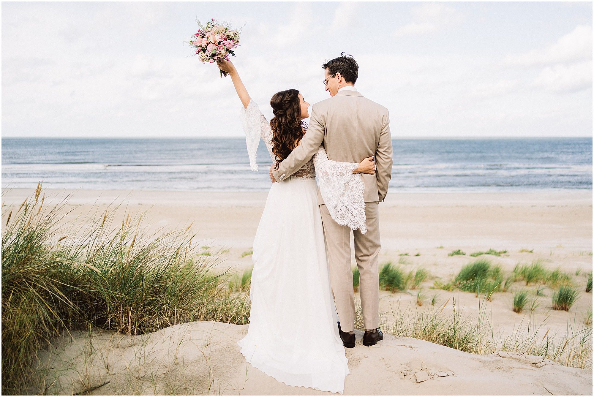 Brautpaar blickt gemeinsam aufs Meer bei einer Inselhochzeit auf Langeoog