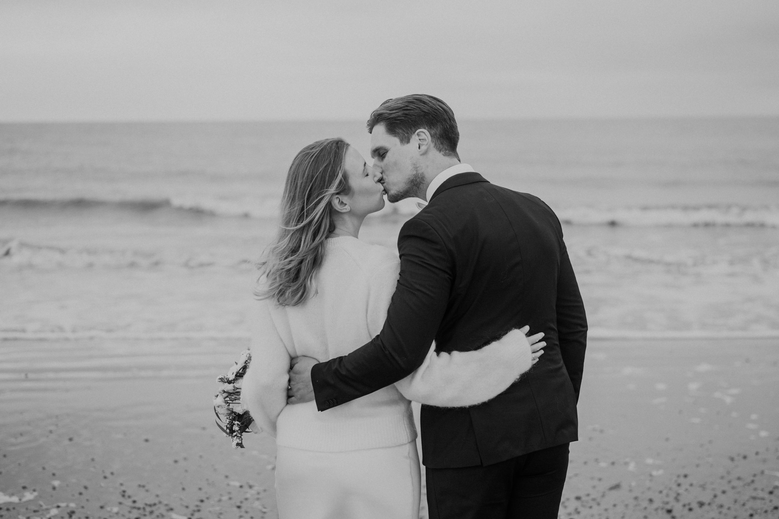 Brautpaar küsst sich eng umschlungen am Meer auf Norderney bei einer Winterhochzeit