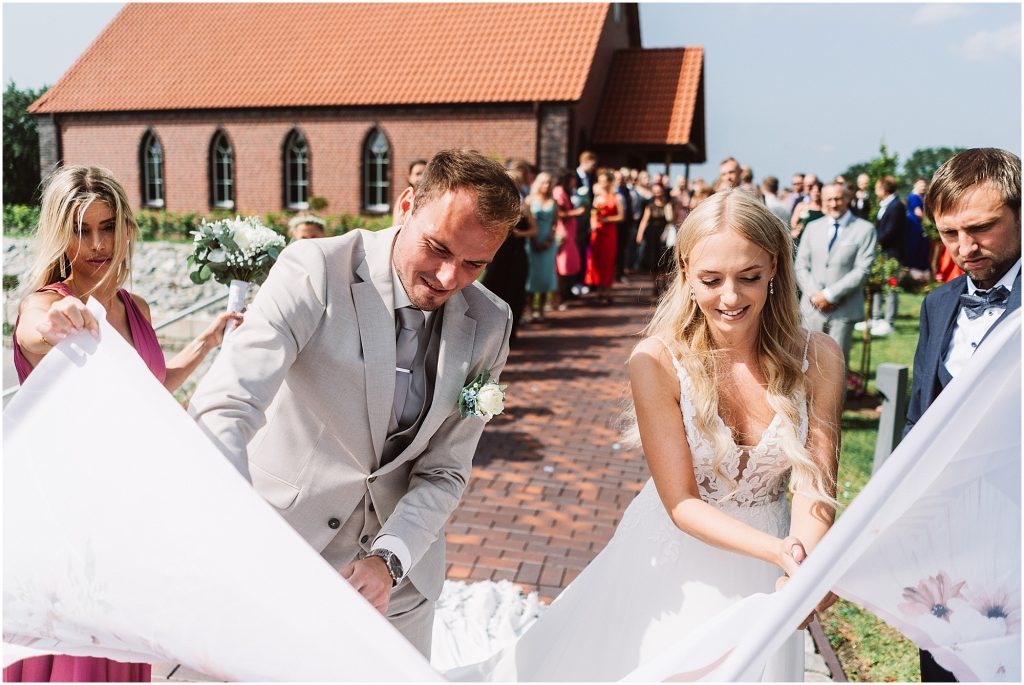 brautpaar beim traditionellen lakenschneiden an der kapelle middels aurich